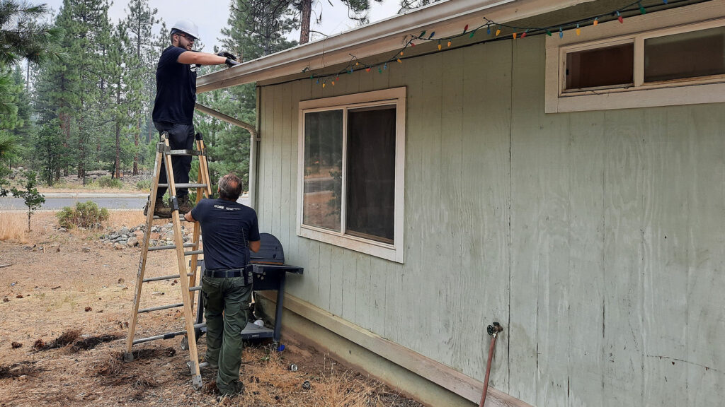 CORE staff members clearing gutters and creating defensible space around a home in Siskiyou County.