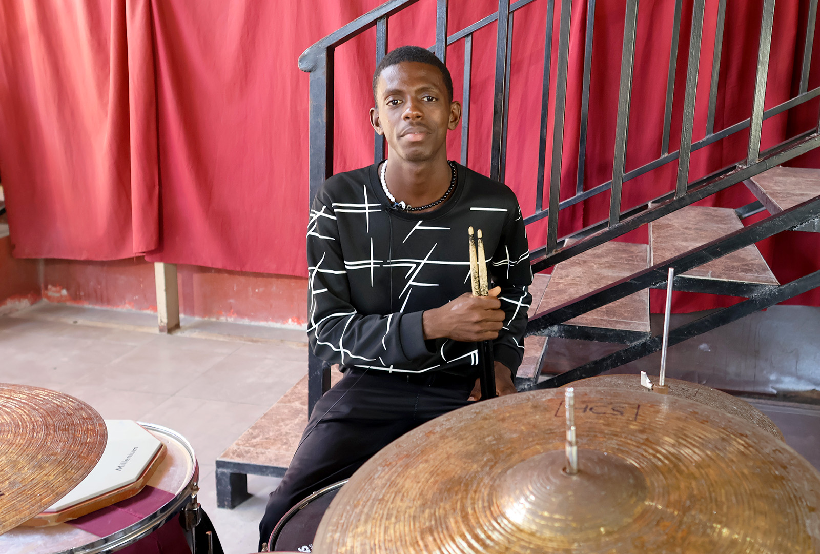 Music student, Marc-Williamson Bijou, poses for a photo as he sits behind his drum kit during practice.