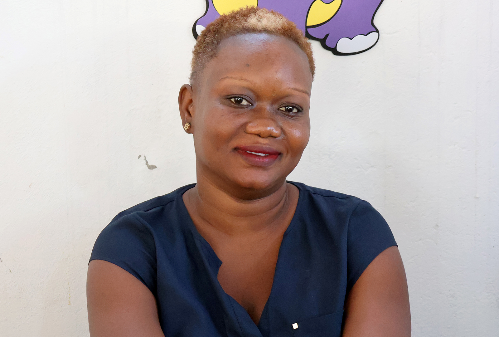 Portrait photo of teacher, Guerda Lubin Pierre Louis, a teacher at the School of Hope and Sunshine sitting inside of her classroom.