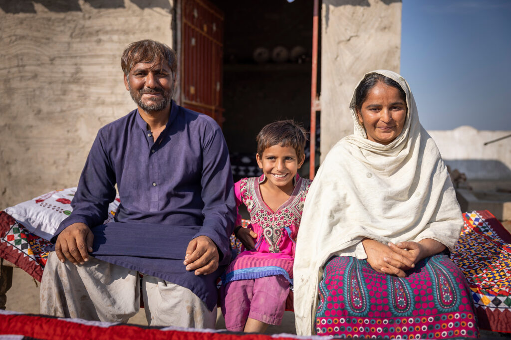 The Azeem family sitting outside of their new home, after the devastating flooding in 2022.