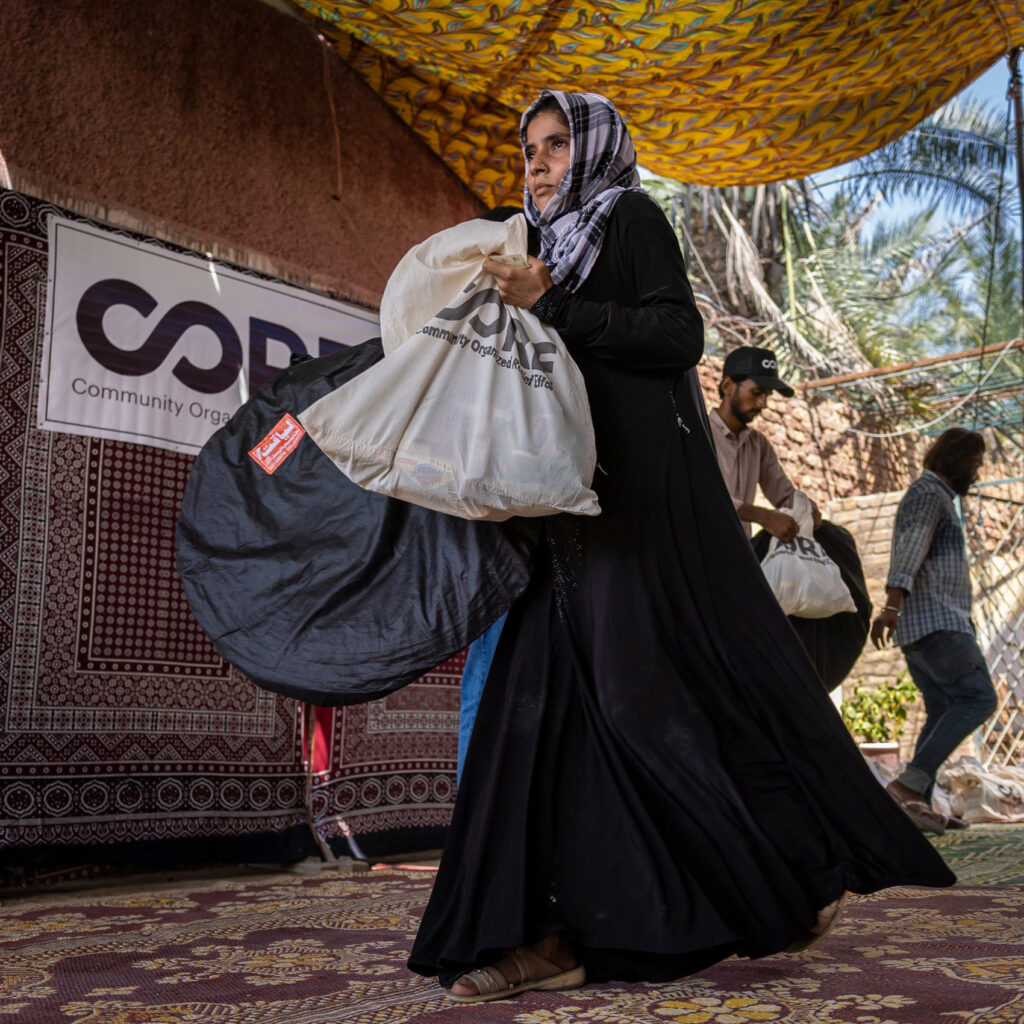 A woman getting supplies and food in Pakistan. The bag which she is carrying has CORE logo in it.