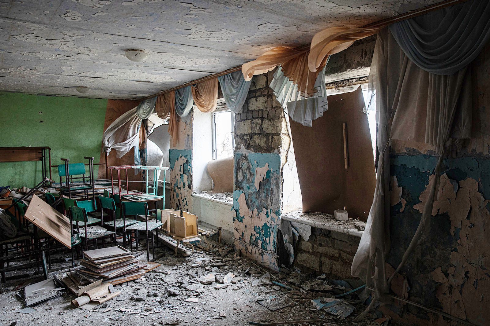 Blown out windows, broken piles of desks, and scattered debris darken the once joyful classroom.