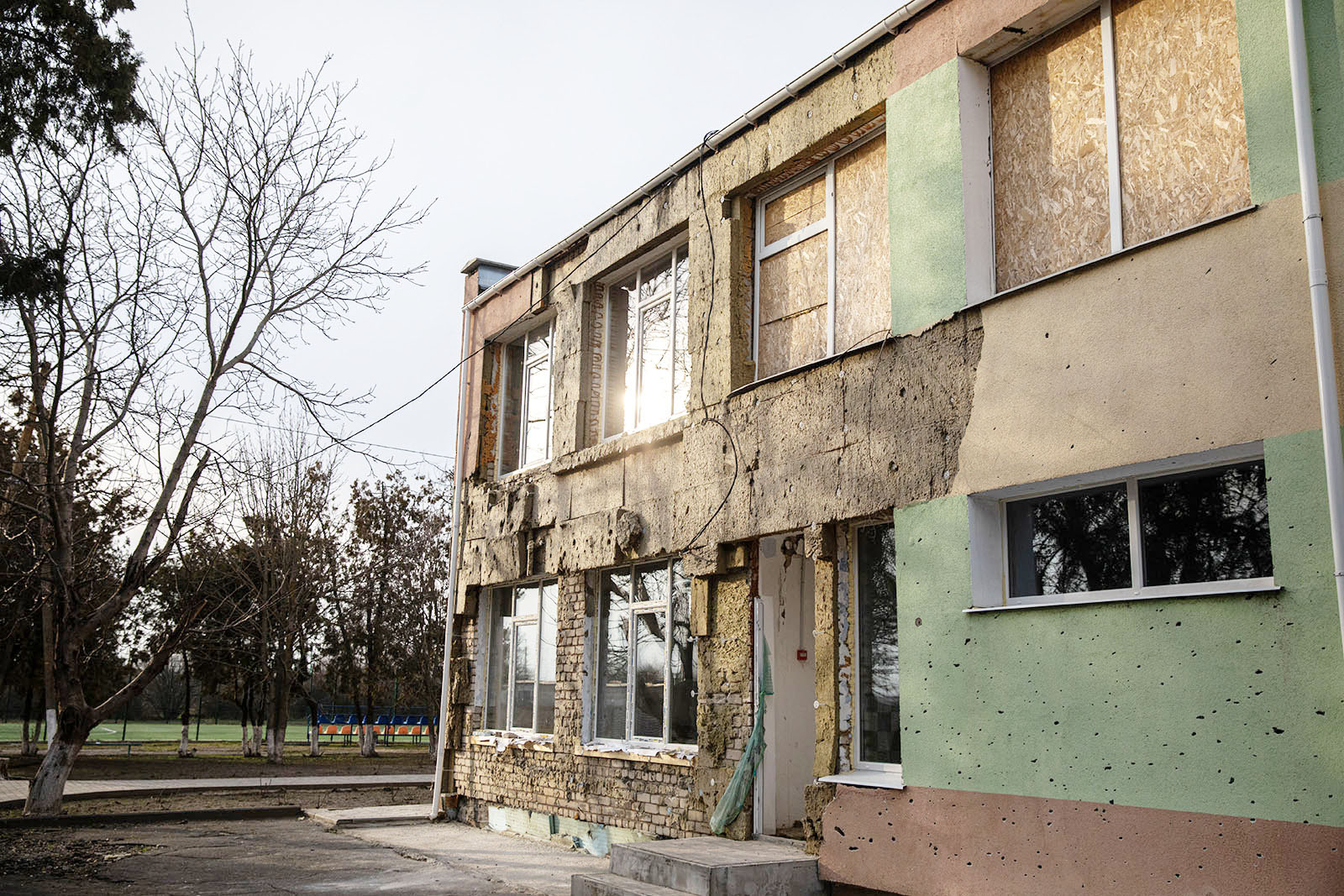 Photo of the school building from the outside showing boarded up windows on the second level and significant damage to the structure on the first level.