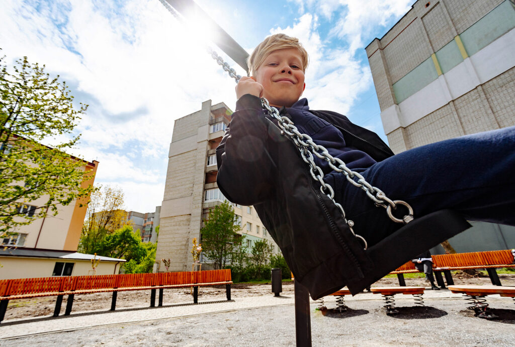 A young boy poses for a photo has he plays on the swings.