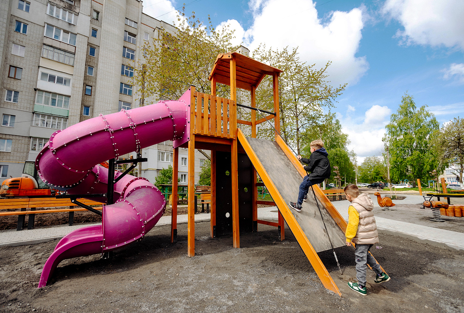 Children climbing up a play structure that includes a slide.