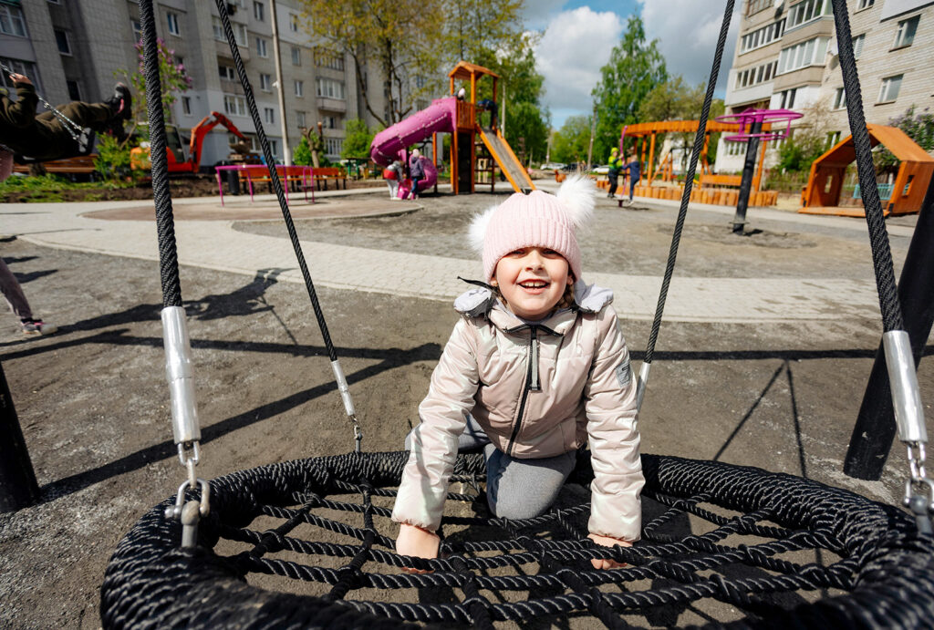 A young girl plays on a circular swing.