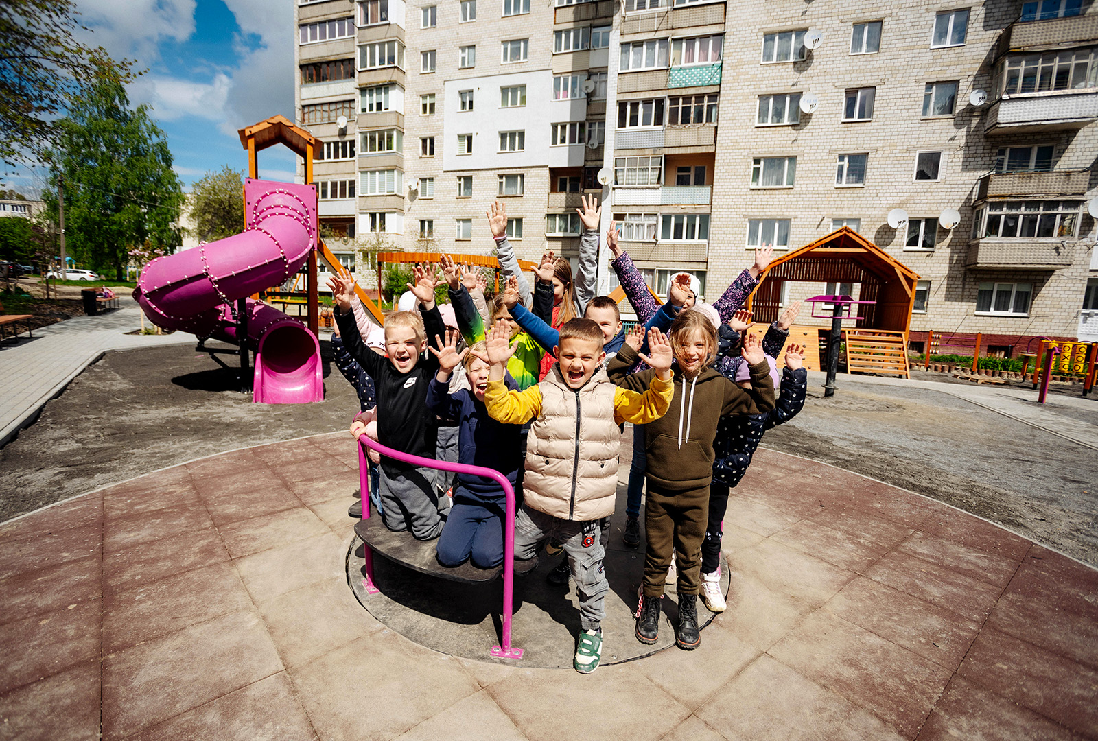 A group of about a dozen children pose on a playground roundabout for a photo in the Ukrainian town of Stebnyk.