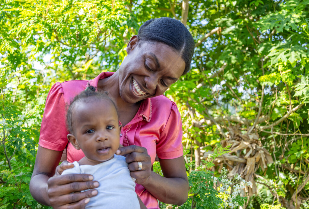 Laurette Senat smiles with her baby daughter on her lap.