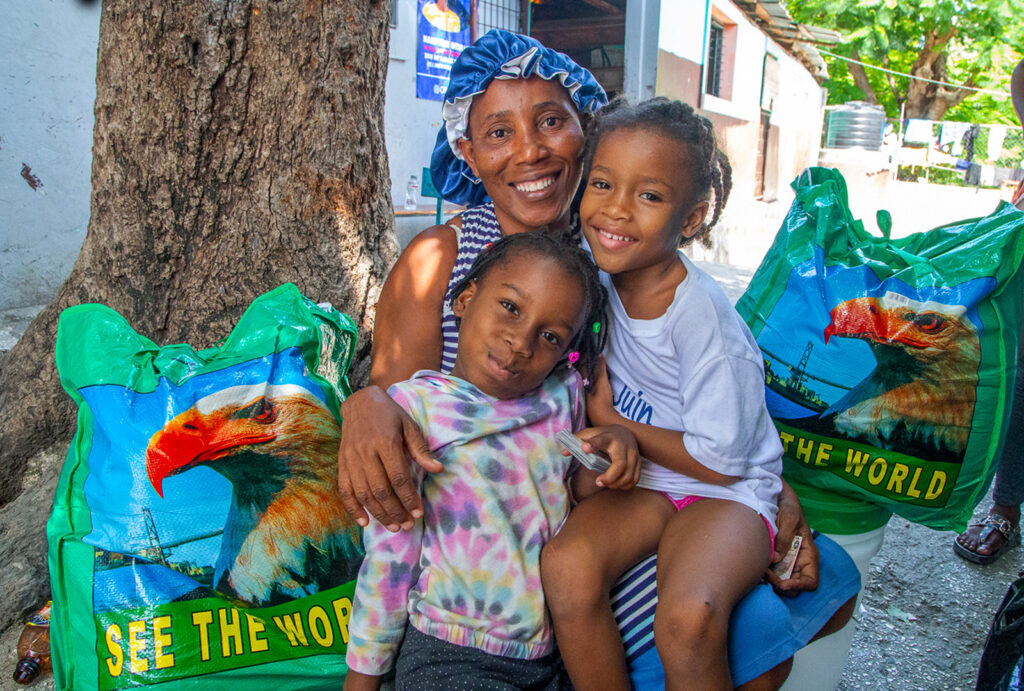 A mother and her two children pose for a photo after receiving food kits from CORE in Port-Au-Prince, Haiti.