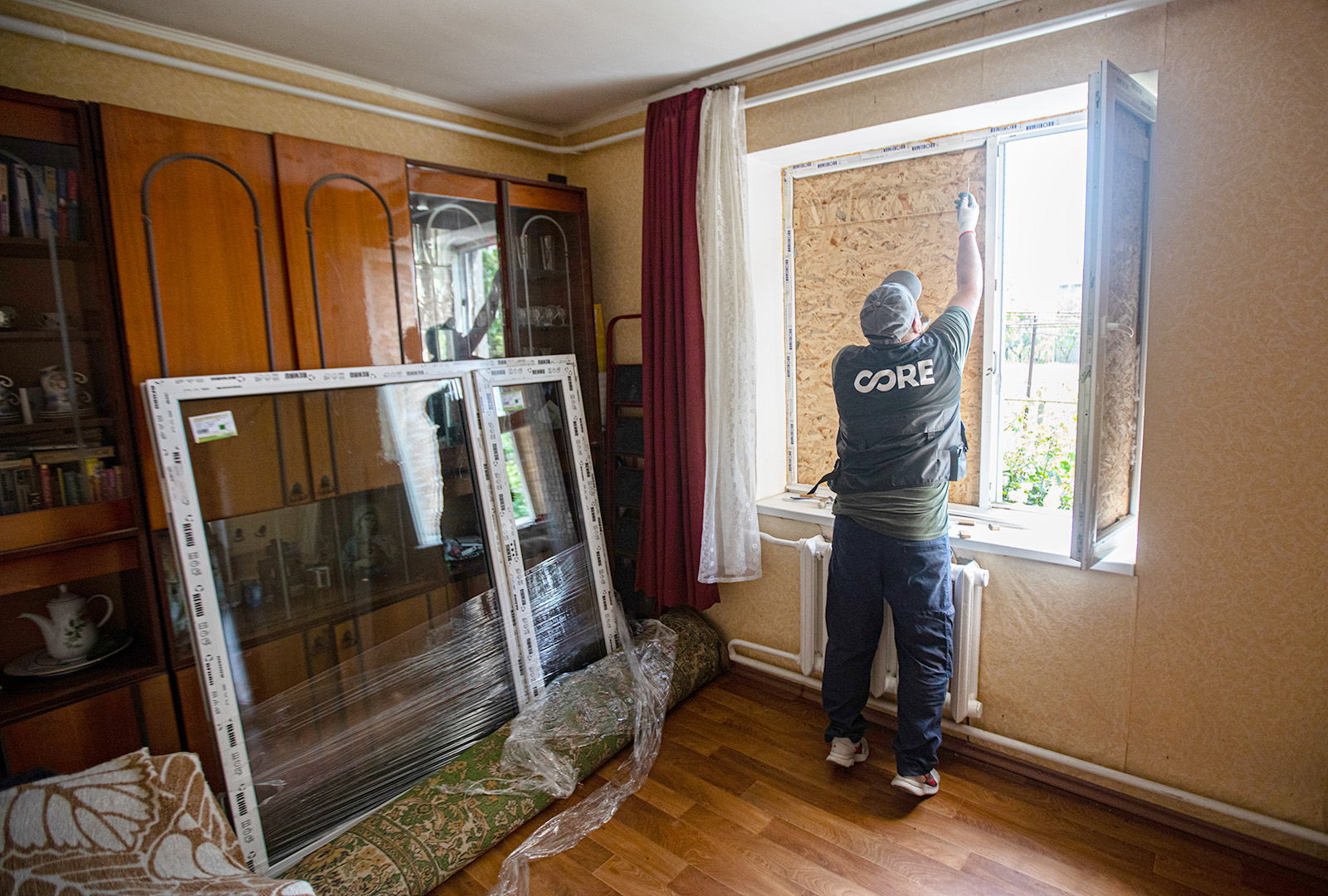 A man measures on opening in a wall to repair windows.