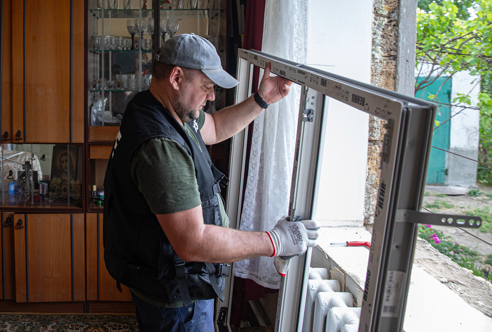 A man places a new window frame in a home un Ukraine.