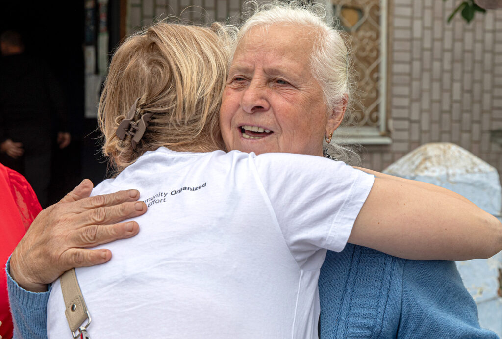 A woman hugs a member of CORE staff after having her windows repaired after they were damaged in the fighting in Ukraine.