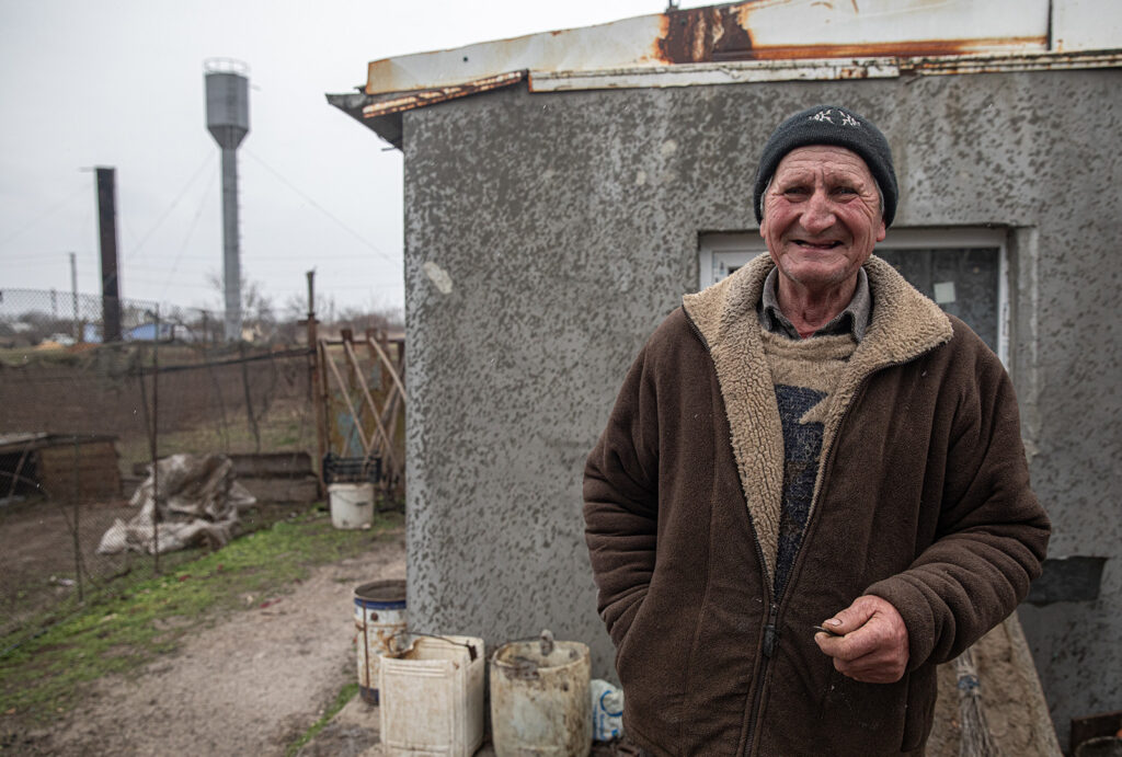 Elderly ukrainian man bundled in winter clothes stands in his backyard in Mykolaiv.