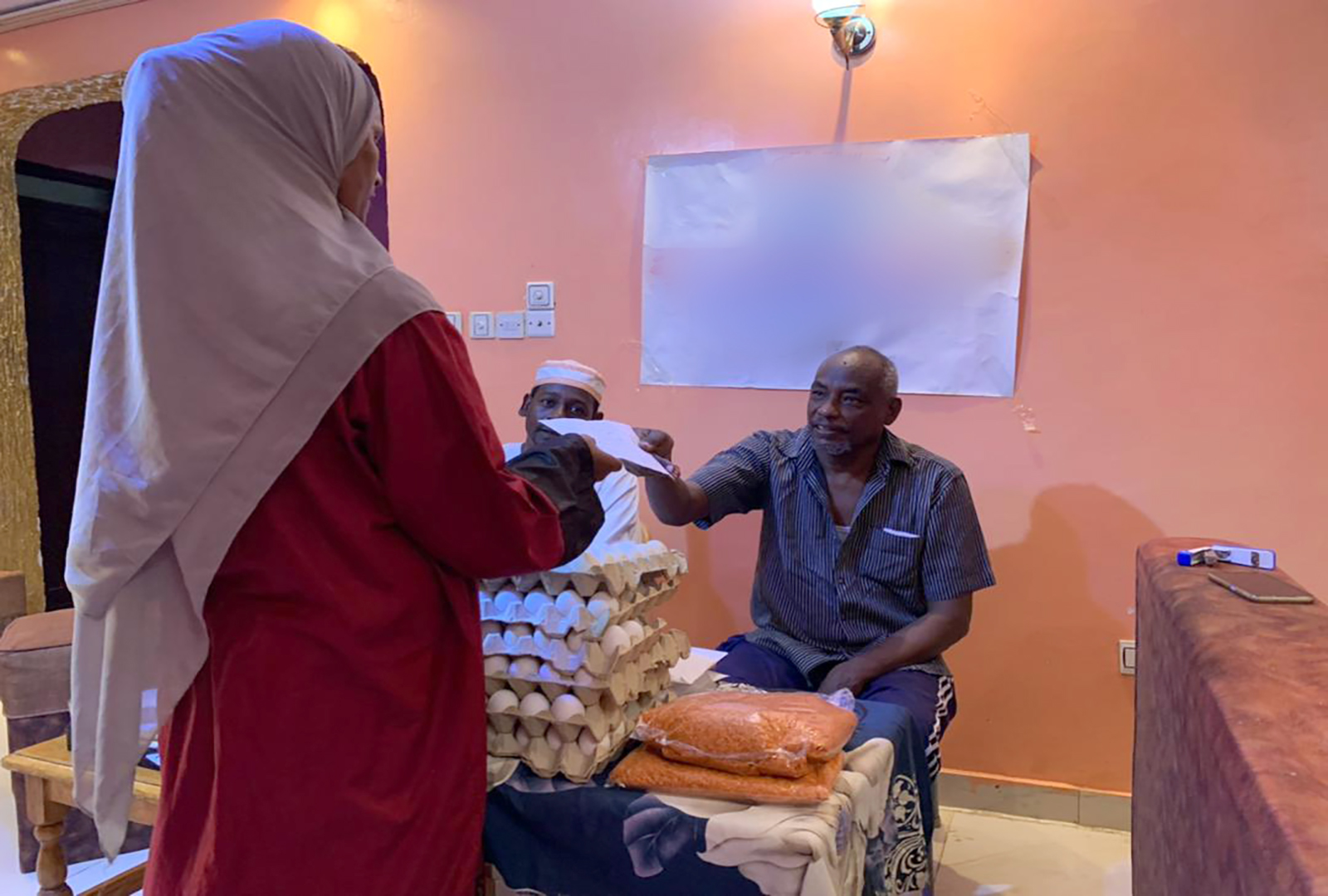 A member of NIDAA's staff supplies a woman with a nutritional voucher at a Women's Response Room in Khartoum.