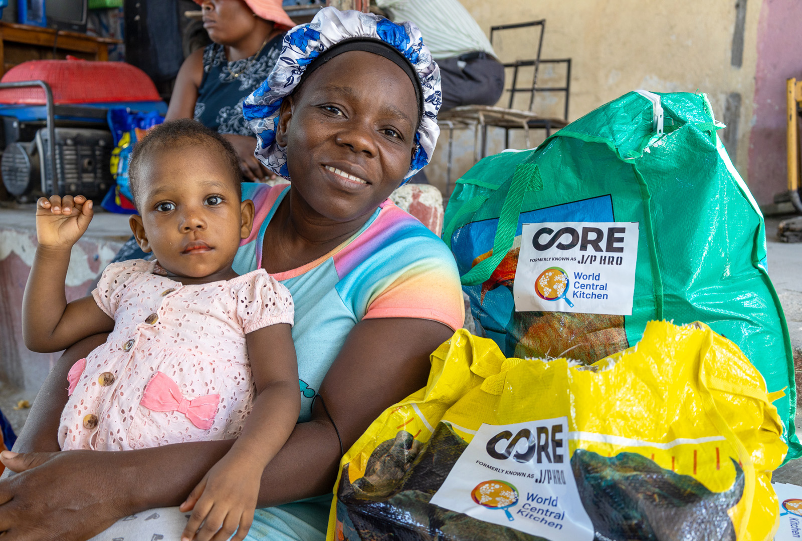 A mother takes a picture with her daughter and the food kit she received to help address the food crisis in Haiti.