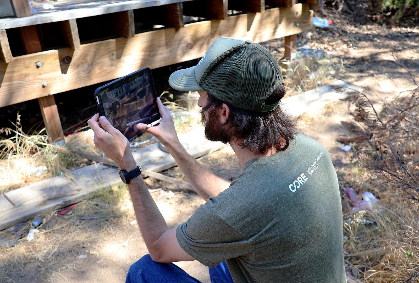 A member of CORE's team holding up a tablet to take a photo during a home assessment in Siskiyou County.