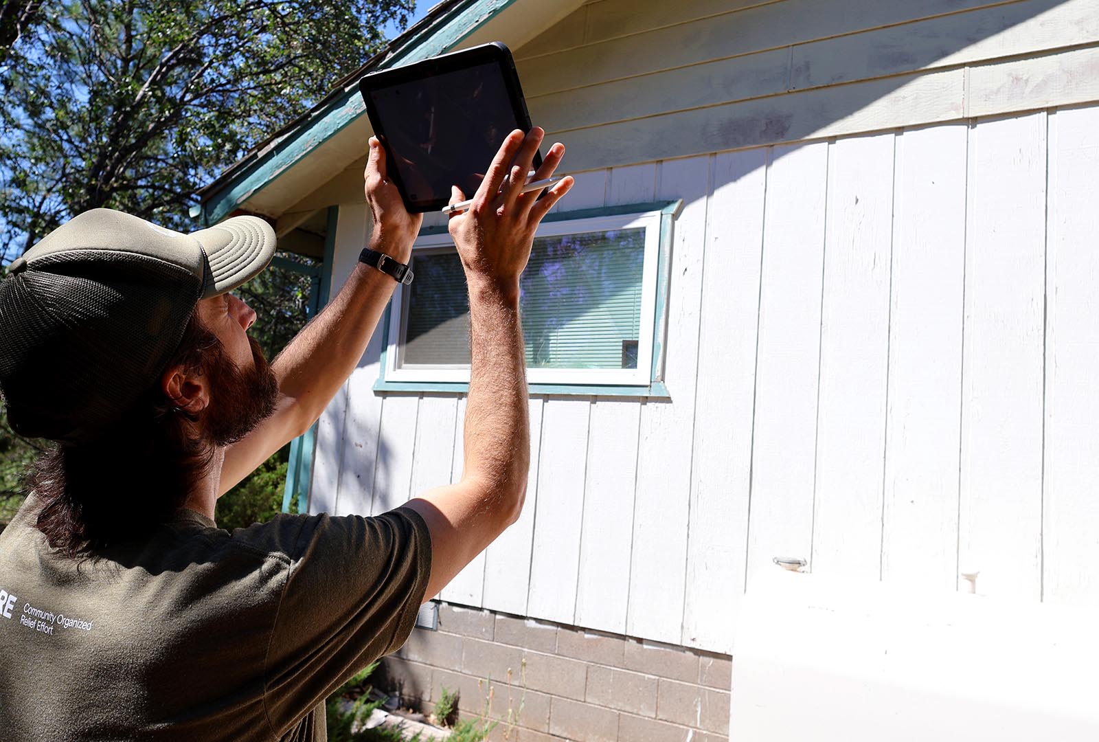 A member of CORE's team holding up a tablet to take a photo during a home assessment in Siskiyou County.