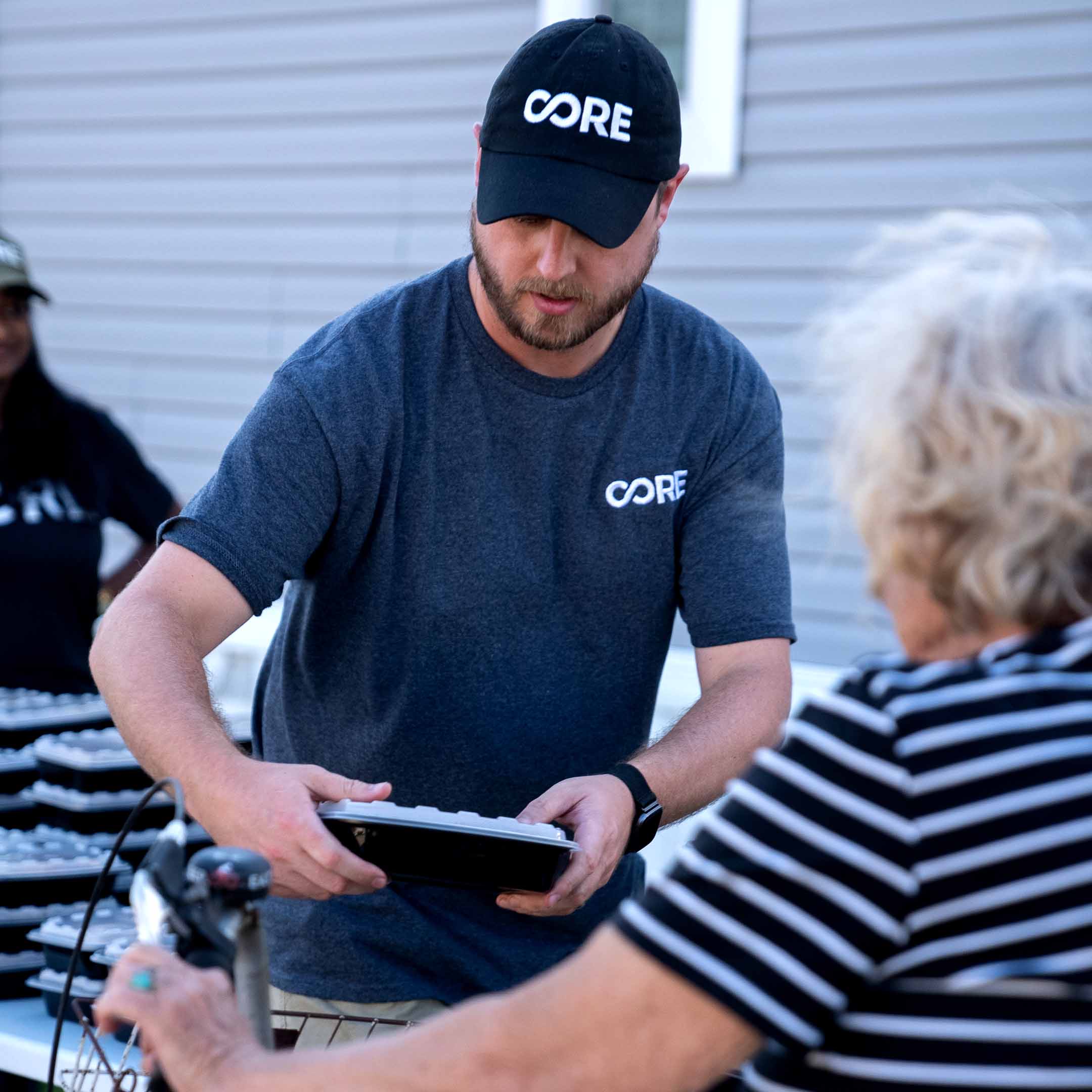 CORE staff hands off a small to-go container of hot food to a older female resident in Pasco County, FL