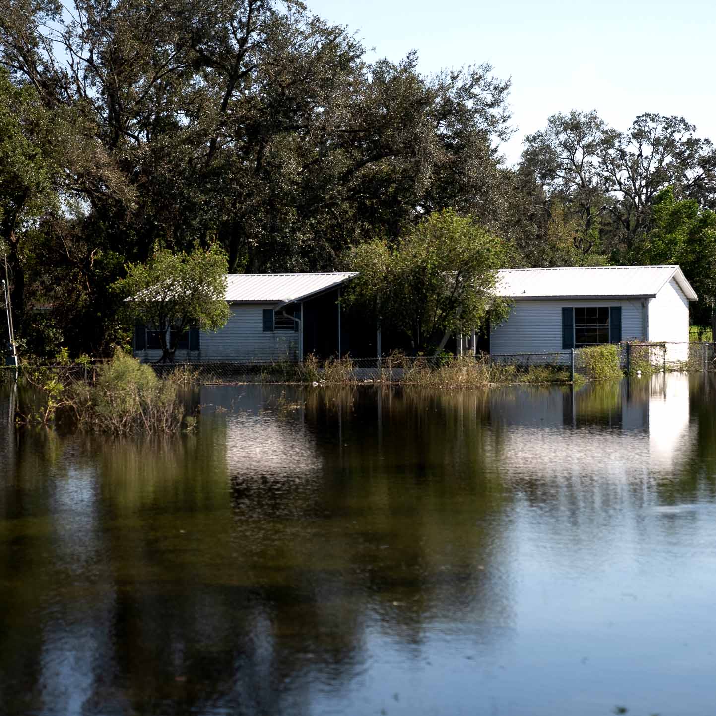 A mobile home is completely surrounding by flood waters up to the door step. There is no non-flooded ground in the shot.