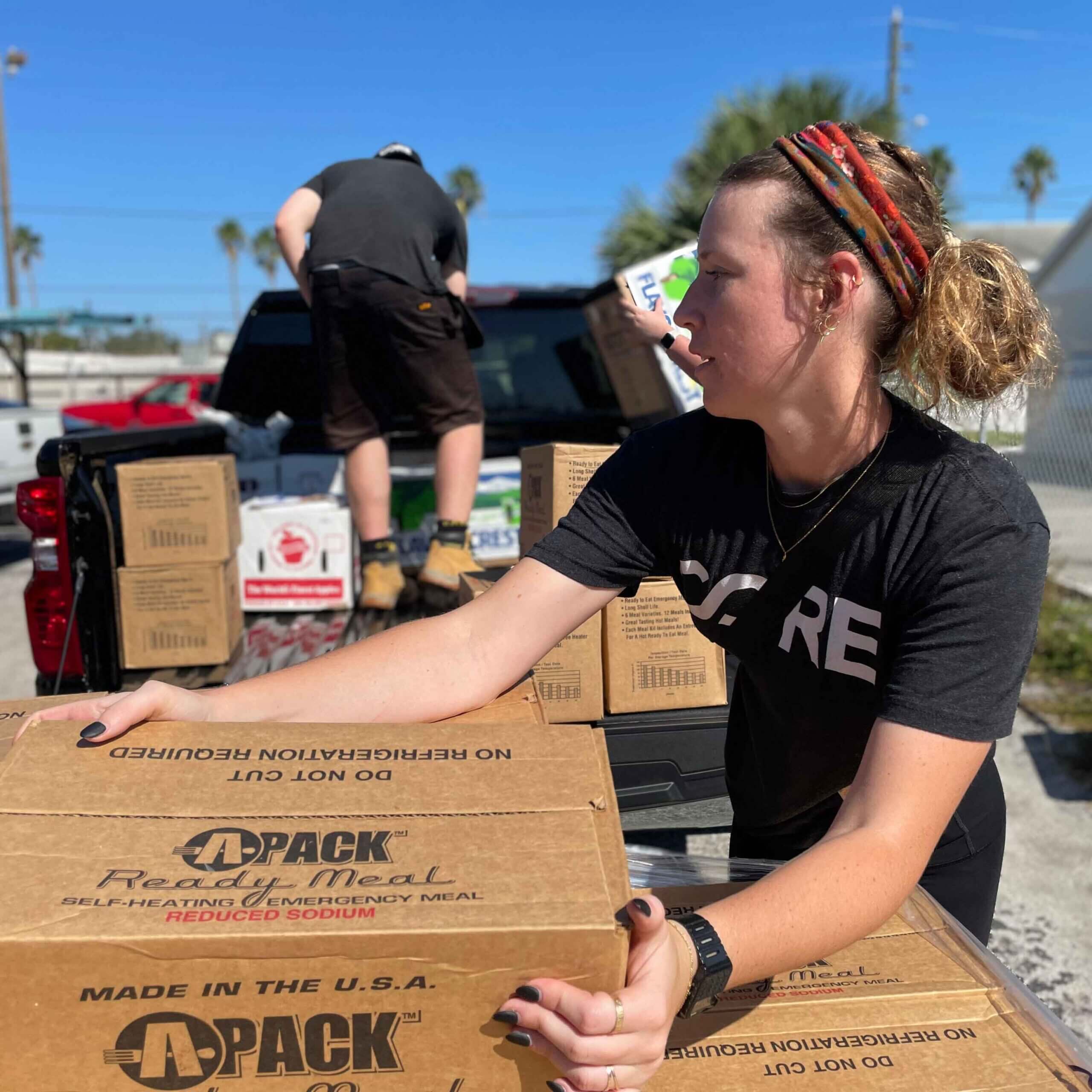 CORE staff picks up a box of ready to eat meals to load into a truck