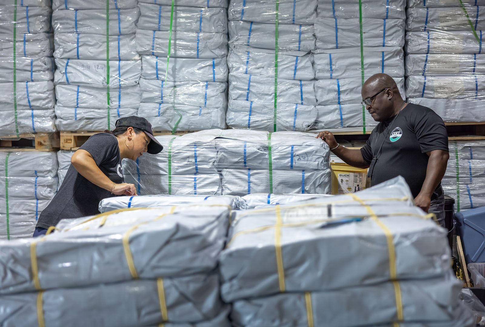 CORE staff in a warehouse with stacks of hundreds of tarps