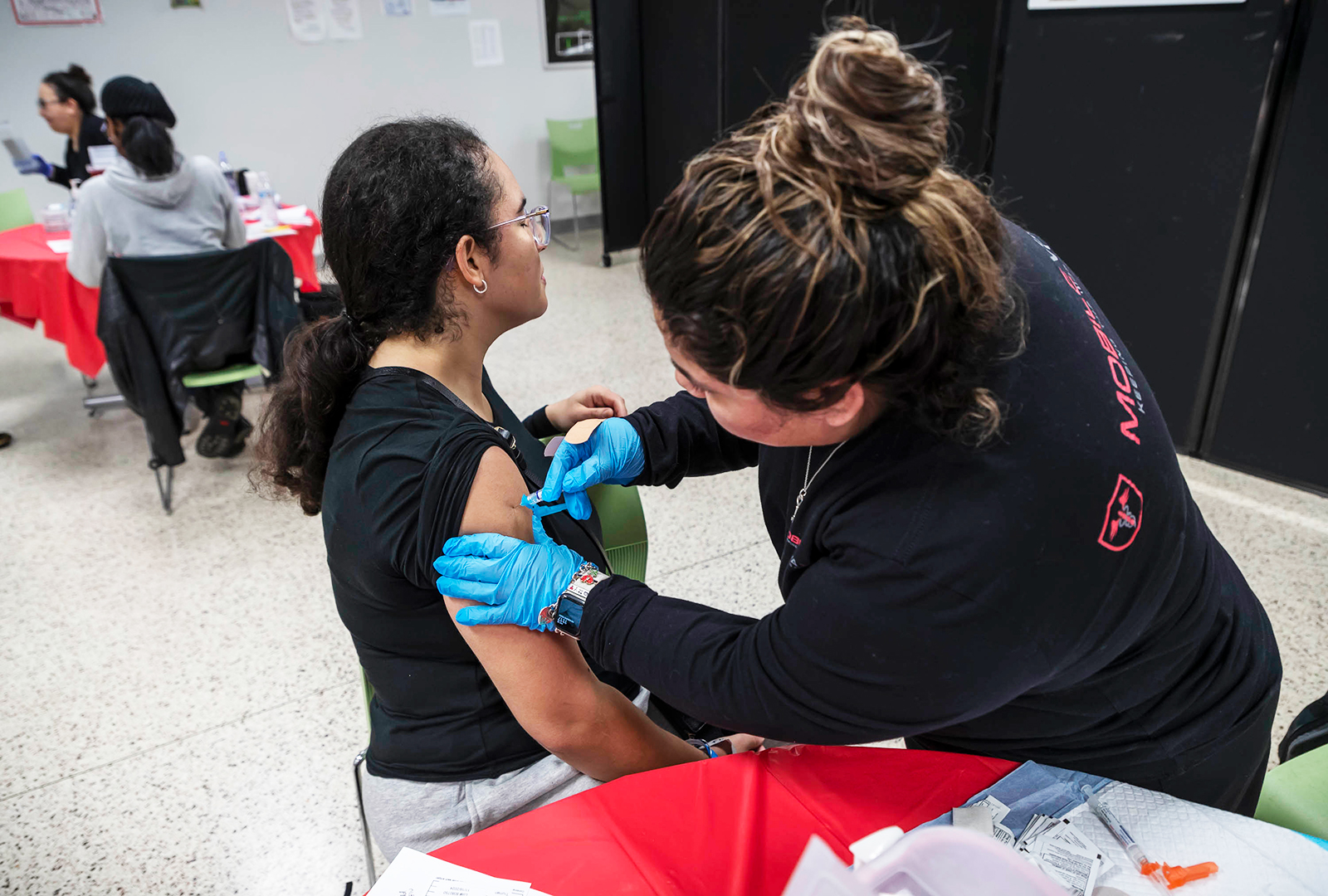 A woman sitting down getting a vaccine.