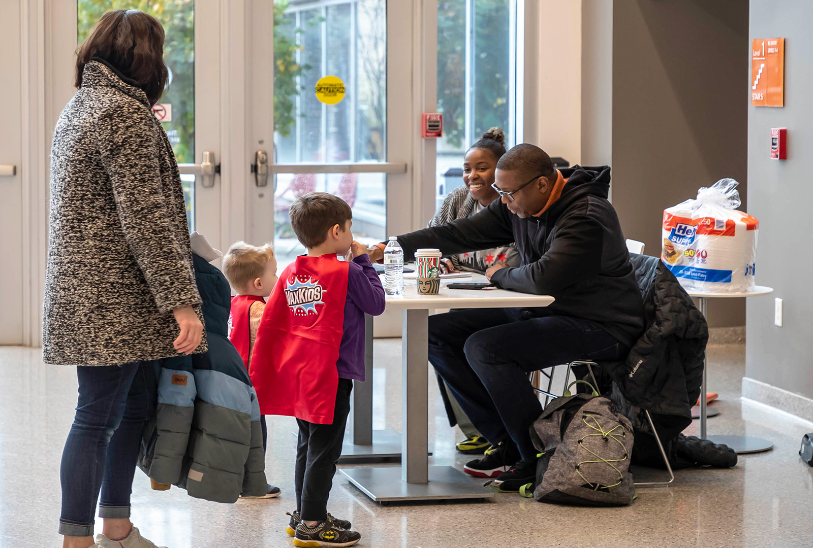 Two boys with capes standing in front of a table at a vaccination clinic in Chicago.