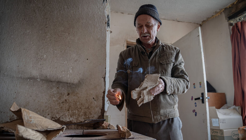 Man uses a match to light firewood in his home