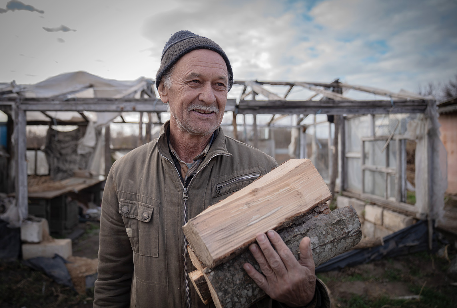 A man standing with pieces of wood that he received from CORE's effort in keeping Ukrainians warm through the winter.