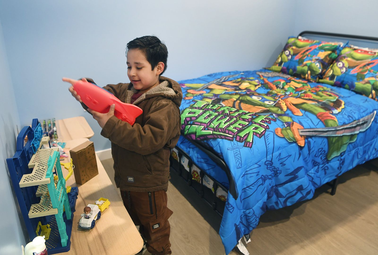 A little boy picks up a toy in his new bedroom