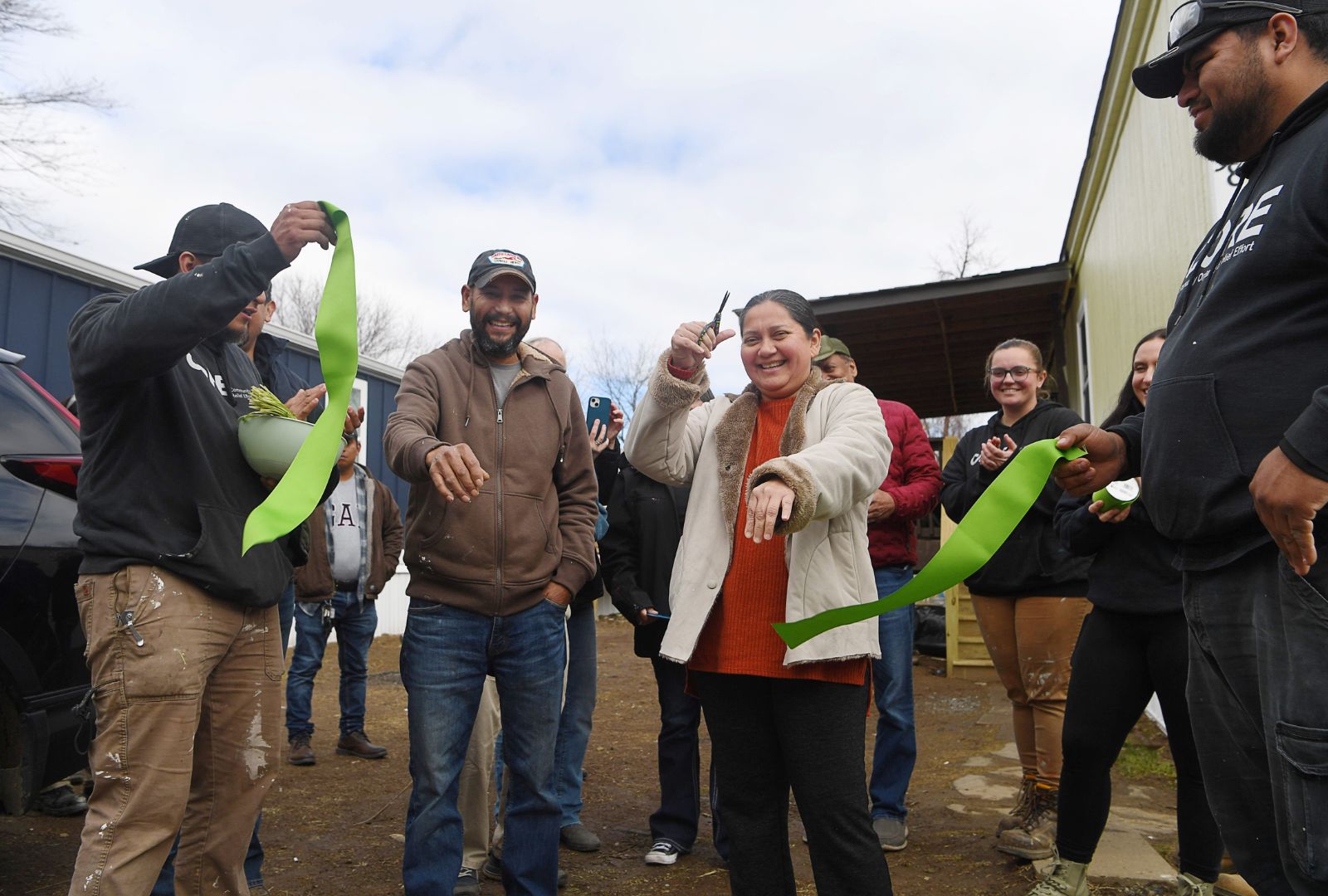 A couple cuts the ribbon celebrating their new home being rebuilt