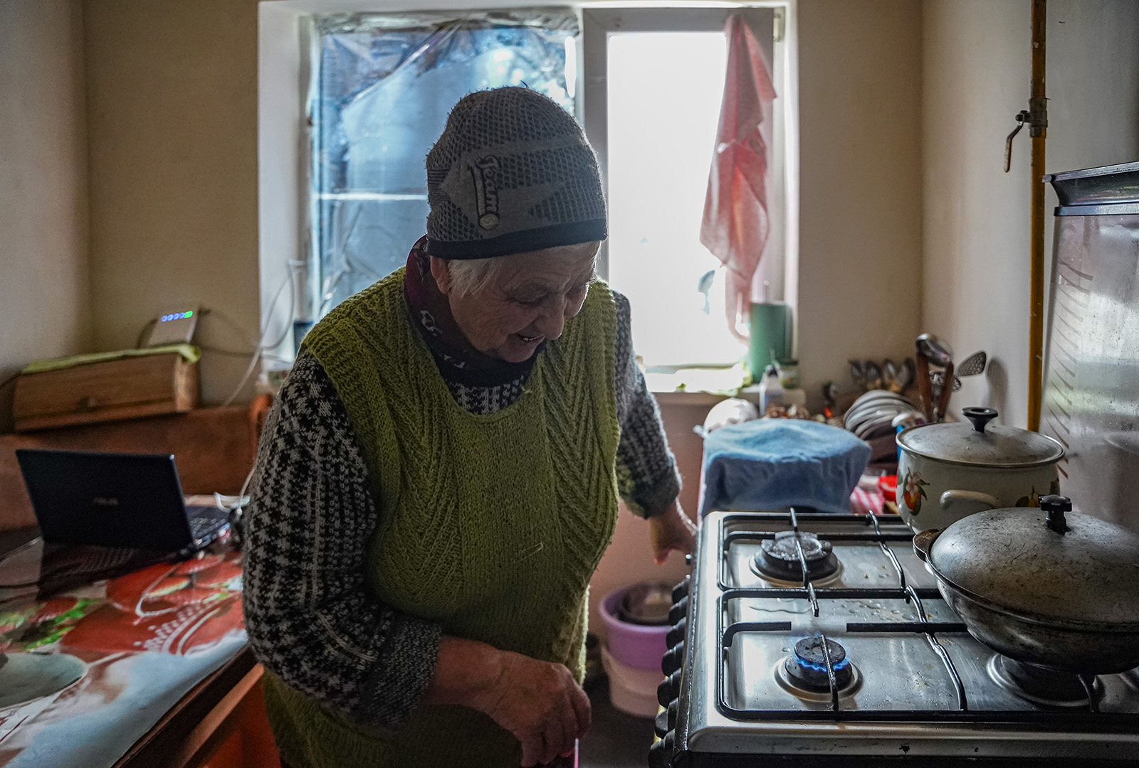 A village resident in Kherson Oblast demonstrates the functioning gas stove in her home after CORE repaired the gas lines to restore access in December 2023.